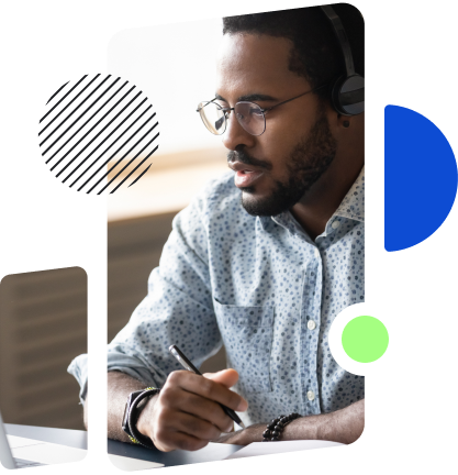 A man wearing a headset and glasses is focused while working on a computer, holding a pen, likely engaged in a virtual meeting or discussion.