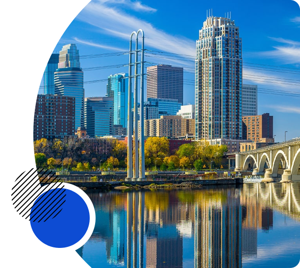 Scenic skyline of Minneapolis, featuring modern skyscrapers and a bridge reflected in the river.