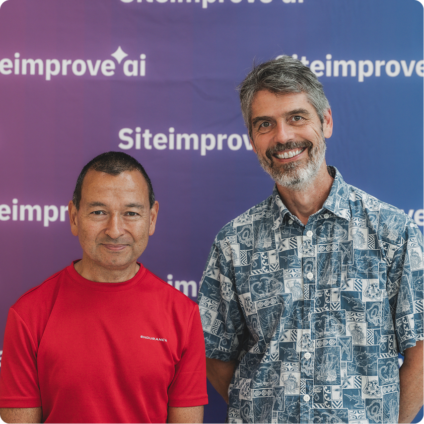 Two Siteimprovers at a company event in front of a Siteimprove backdrop.